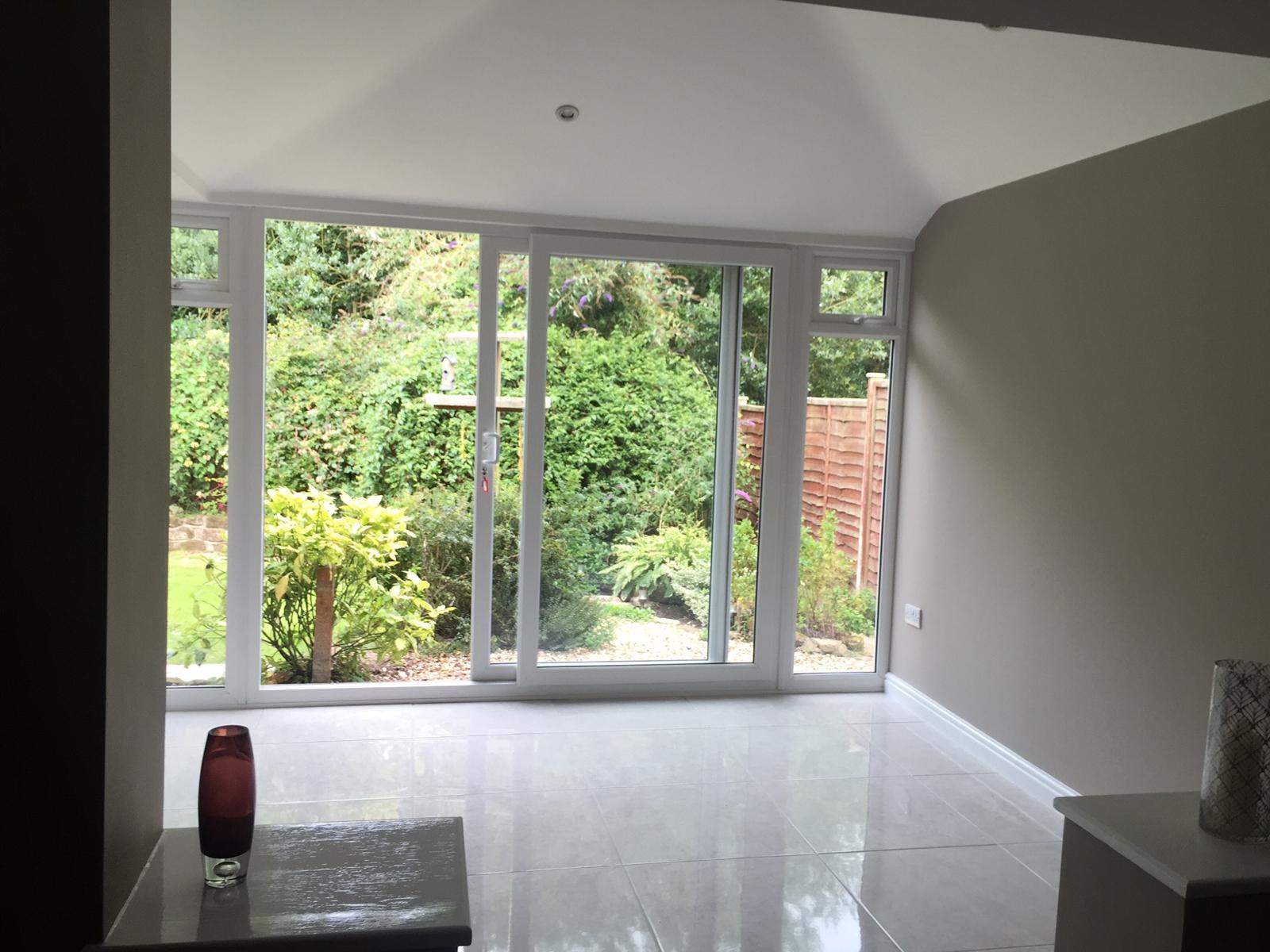 Inside a finished Smart-Roof conservatory with vaulted ceiling and full-height garden view