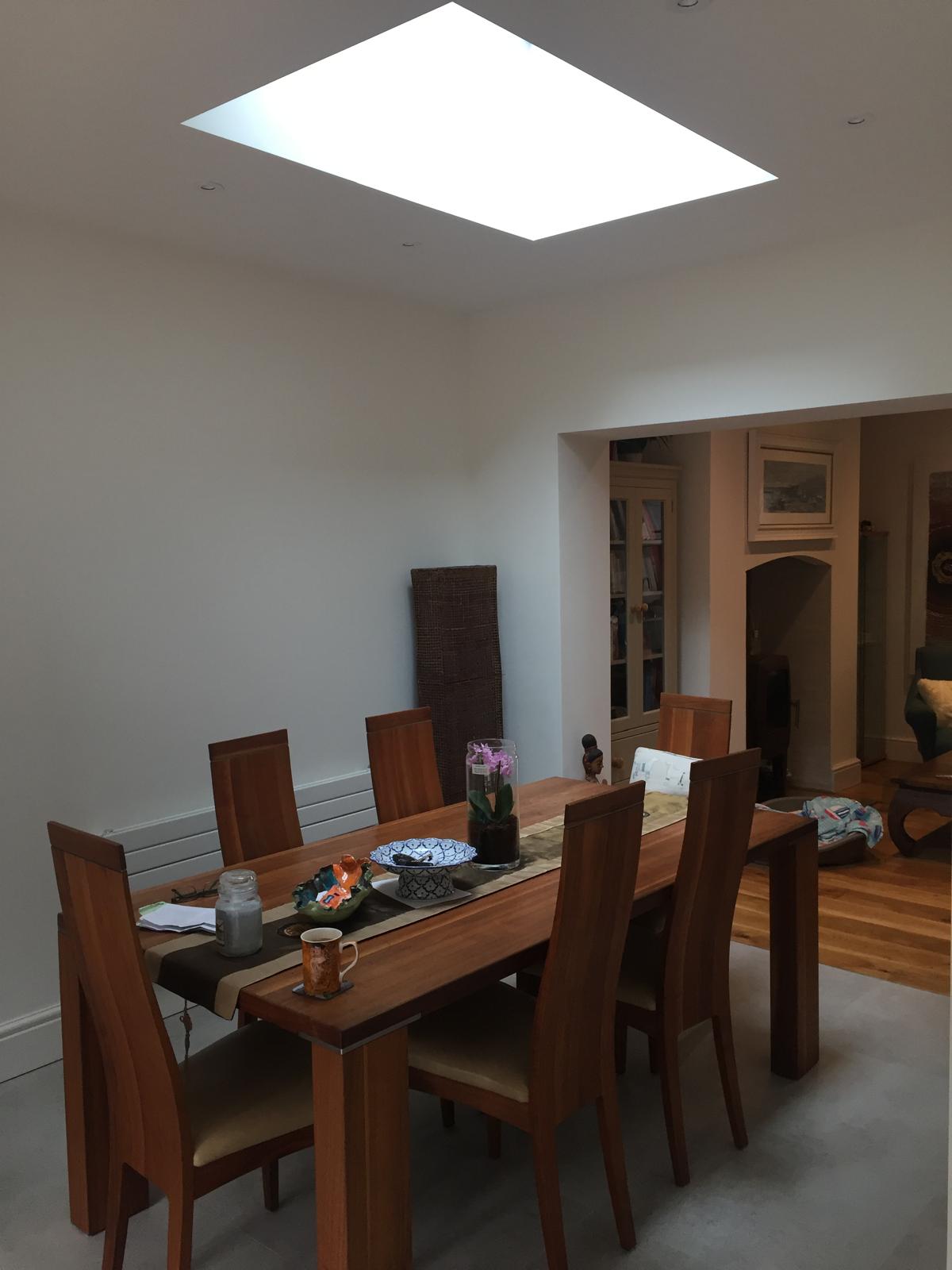 Solid roof conservatory dining area with large flat skylight flooding the room with daylight